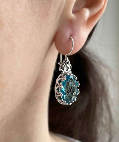 Silver oval drop earrings with filigree blue topaz gemstones and a crown-shaped design for women.
