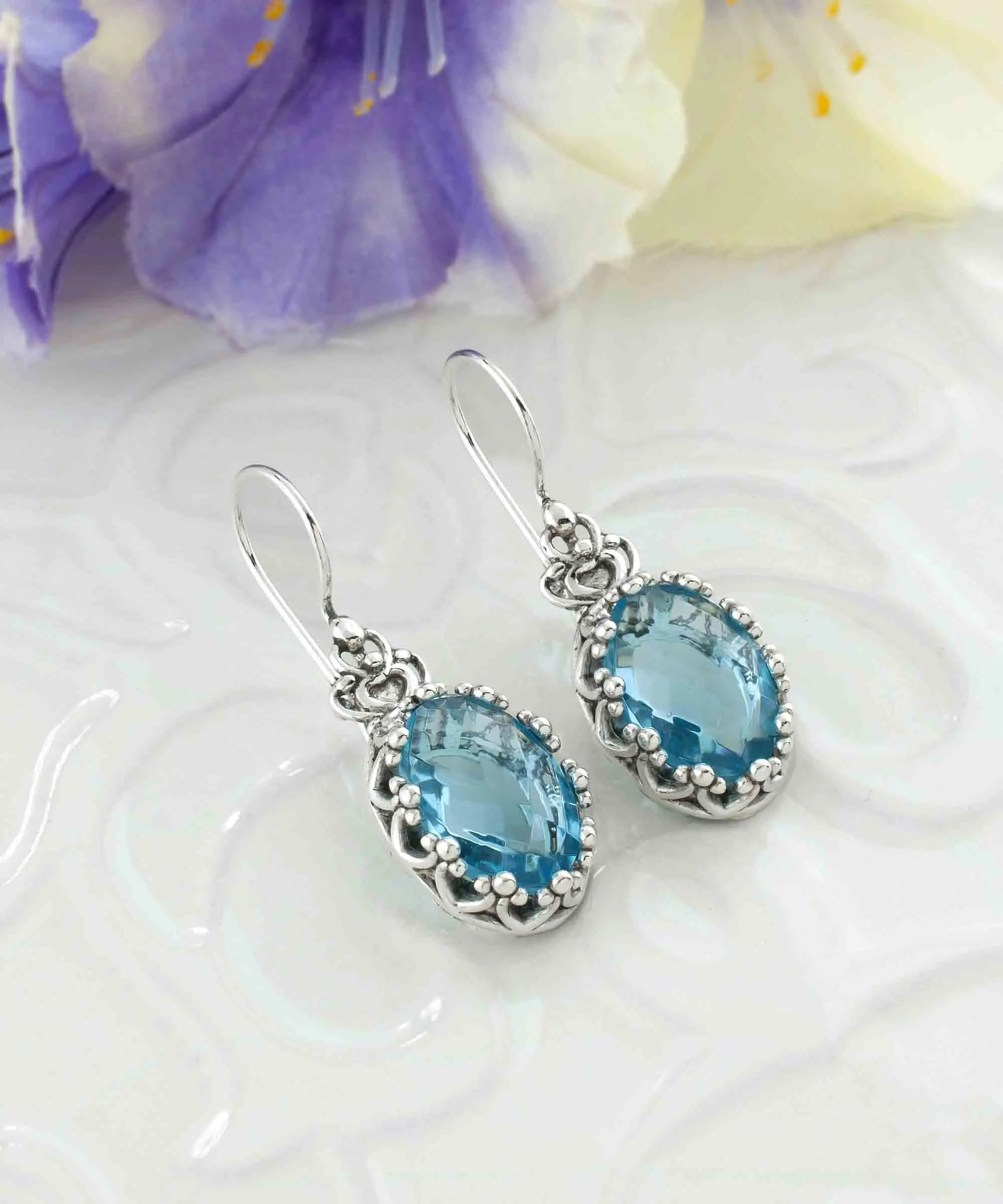 Silver drop earrings featuring filigree art, blue topaz gemstones, and a crown design for women.