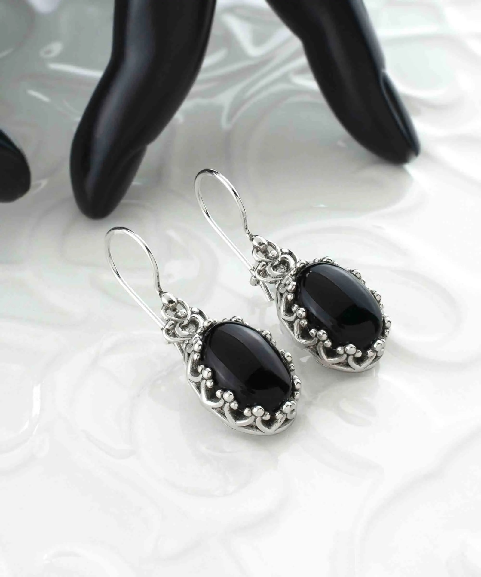 Silver drop earrings with black onyx gemstones, intricate filigree design, and crown-shaped details for women.