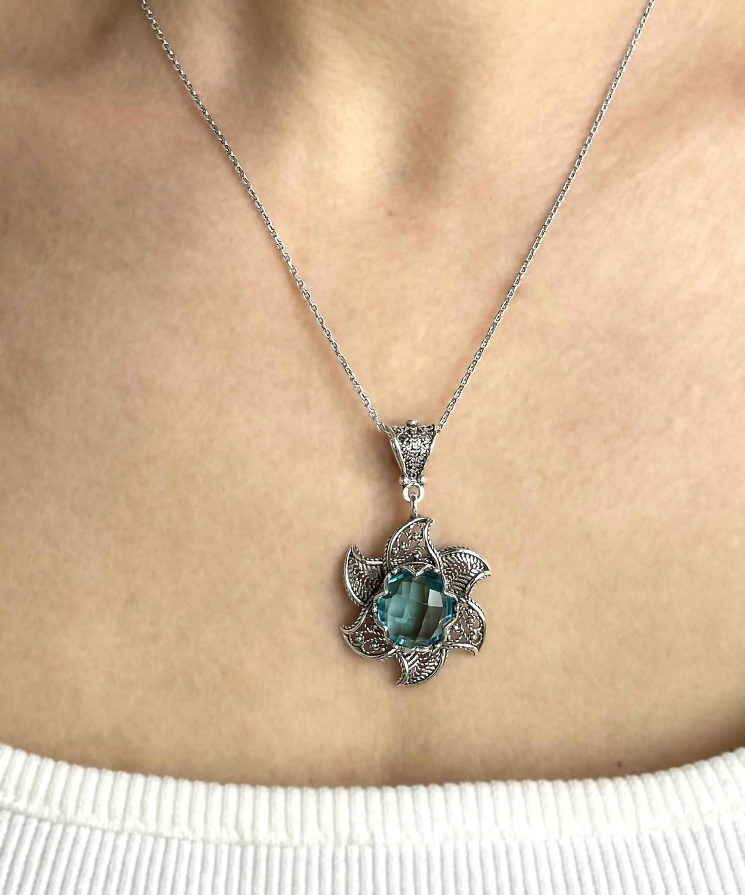Sterling silver filigree pendant necklace with blue topaz gemstone blossom lotus flower design, intricate jewelry piece.