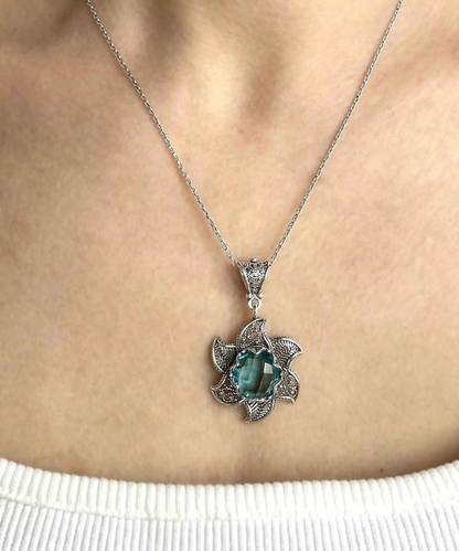 Sterling silver filigree pendant necklace with blue topaz gemstone blossom lotus flower design, intricate jewelry piece.