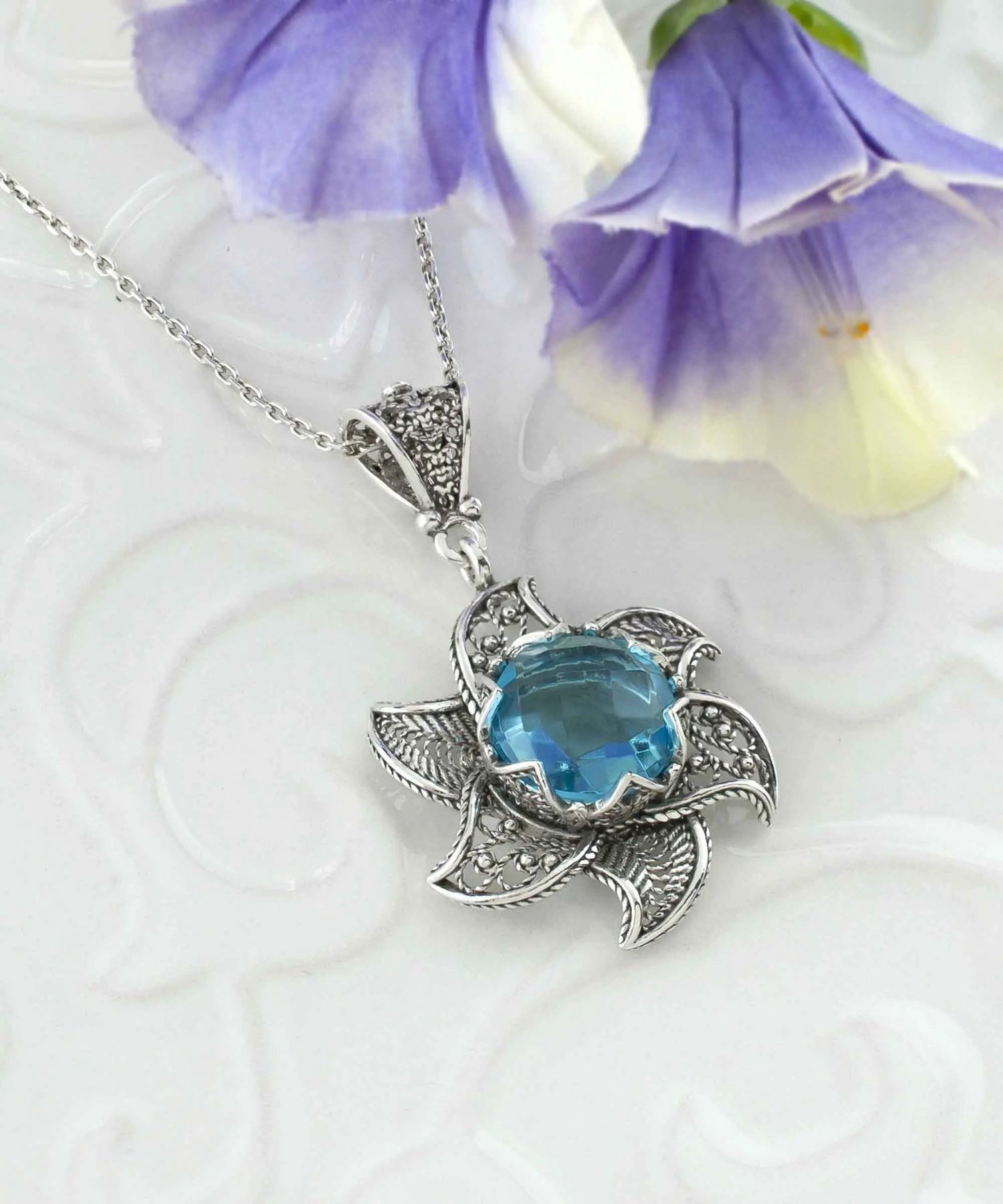Sterling silver filigree necklace featuring a blue topaz gemstone blossoming lotus flower pendant, elegant jewelry piece.