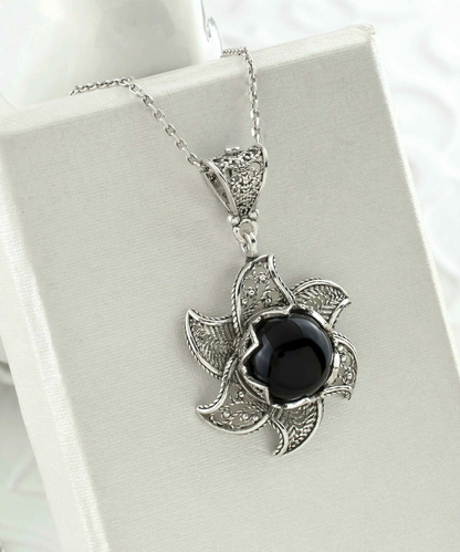 Sterling silver filigree lotus flower pendant with black onyx gemstone, detailed jewelry necklace, elegant and blossoming design.