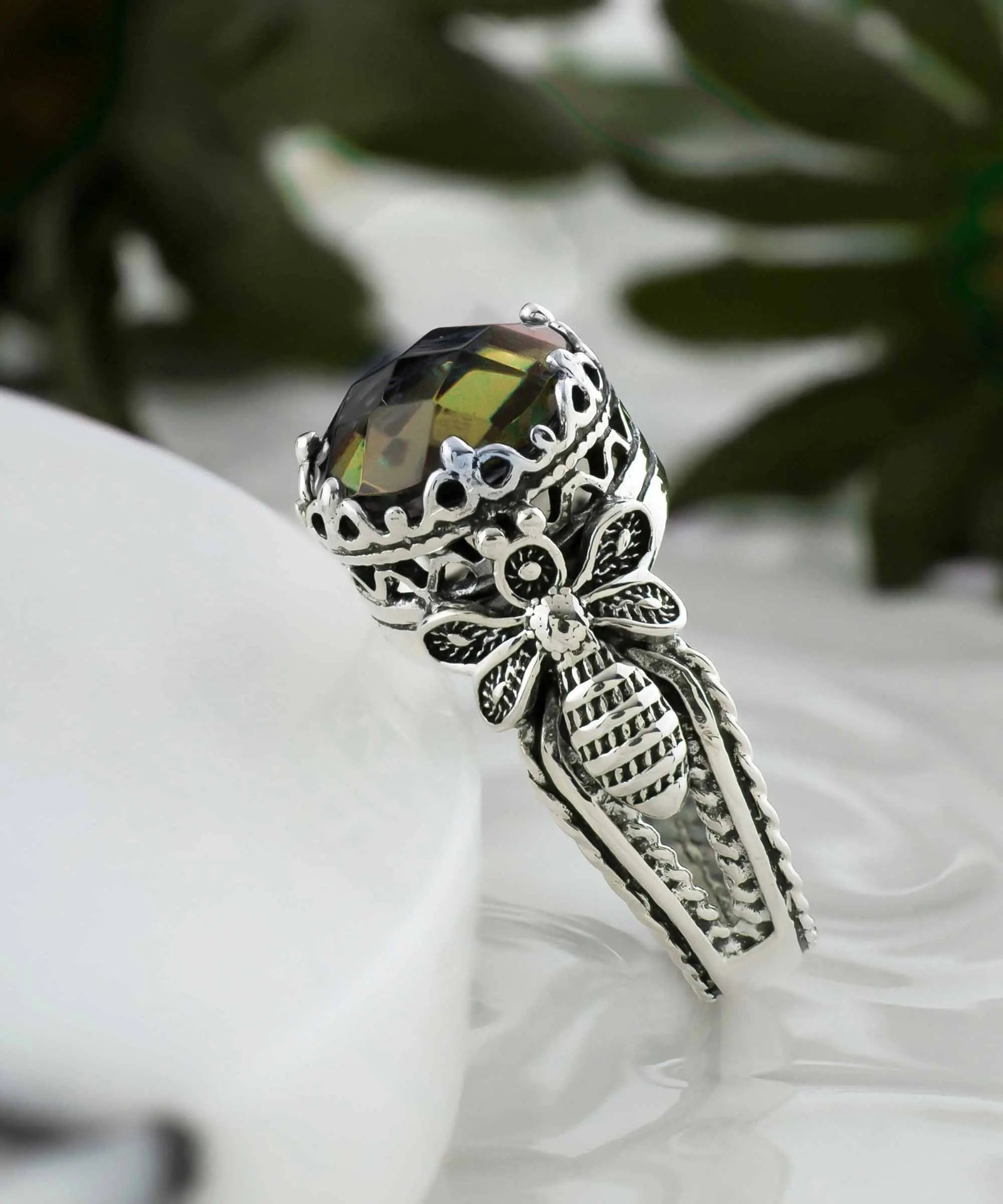 Silver cocktail ring with detailed bee and alexandrite gemstone filigree design, worn by a woman, showcasing intricate jewelry craftsmanship.