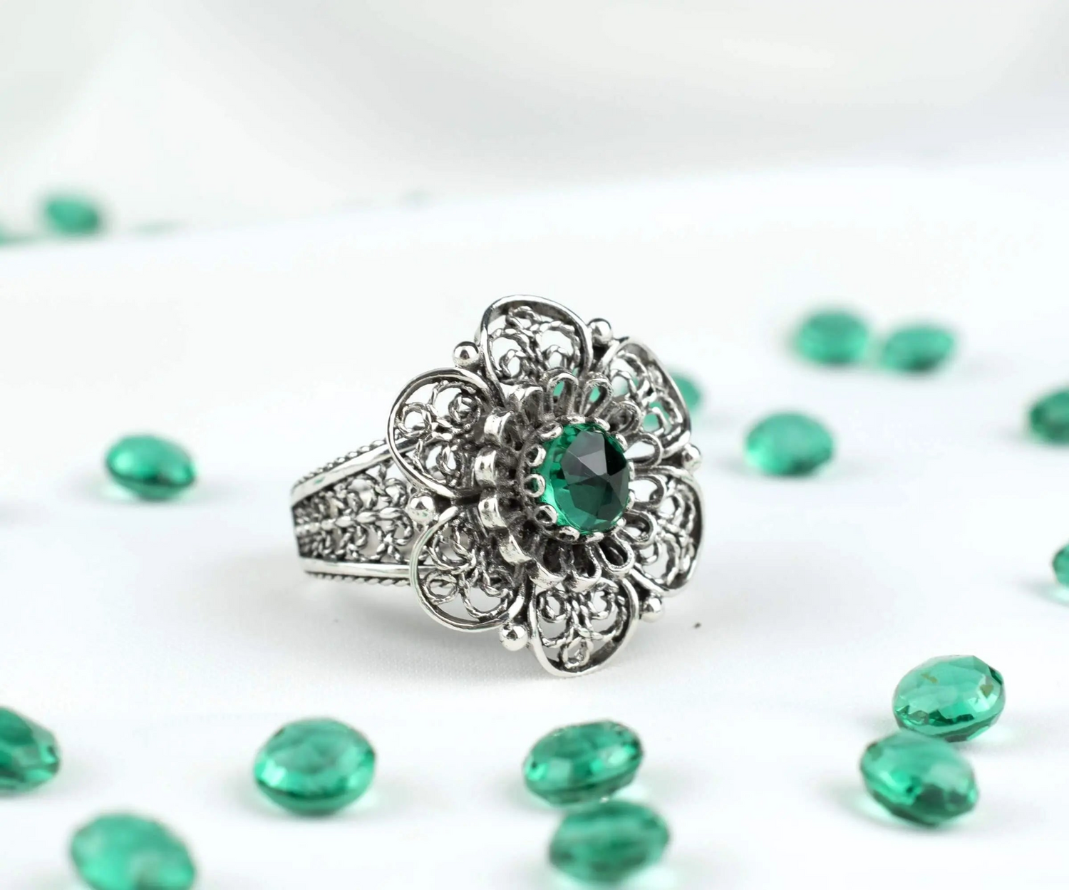 Silver statement ring with filigree art and emerald gemstone for women, featuring intricate jewelry design.