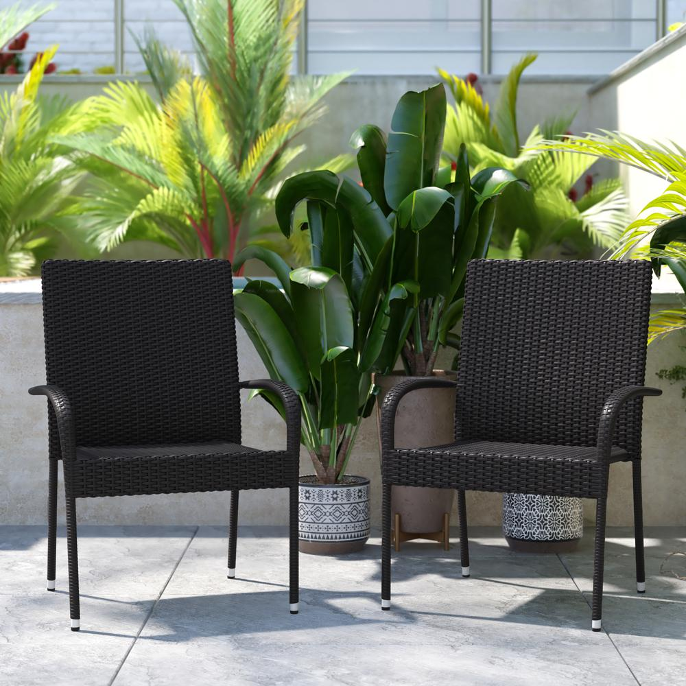Set of two black stackable wicker dining chairs with armrests, weather-resistant steel frames for indoor or outdoor use.