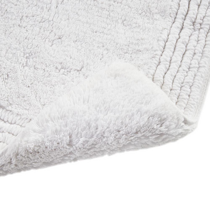 Reversible bath rug made of 100% cotton with 3000 GSM, featuring a tufted design and plush texture in neutral colors.