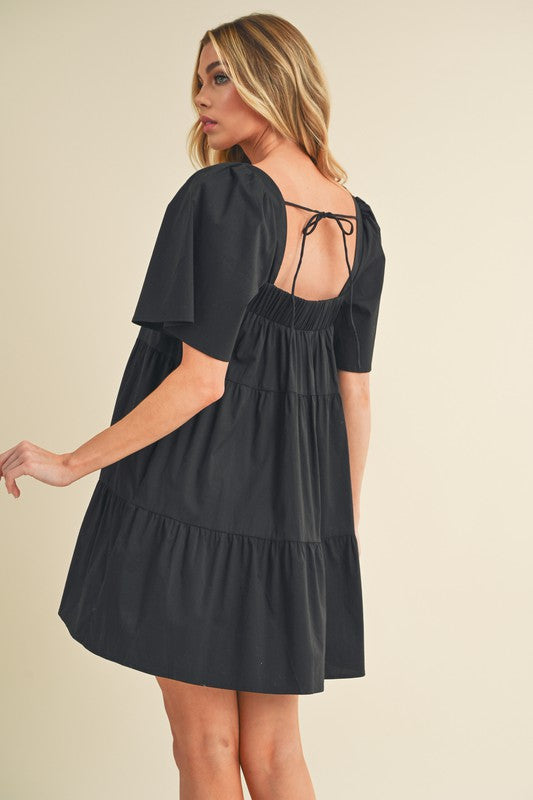 A woman wearing the Jade Icarus Aemi + Co square neck half sleeve tiered dress, showcasing its relaxed fit and tiered design.