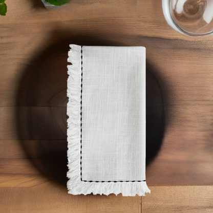 Set of four home table cloth napkins with elegant black embroidery, showcasing detailed stitching and soft fabric texture.