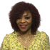 Peach Clymene Kelly curly human hair wig with bangs, full volume, showcasing glossy, styled hair with soft curls and layered bangs.