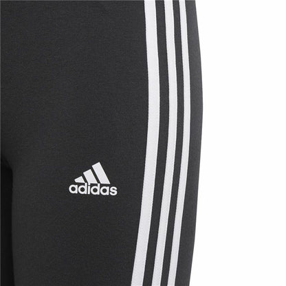 Black Adidas Essentials sports leggings with three white stripes, designed for activewear and outdoor activities.