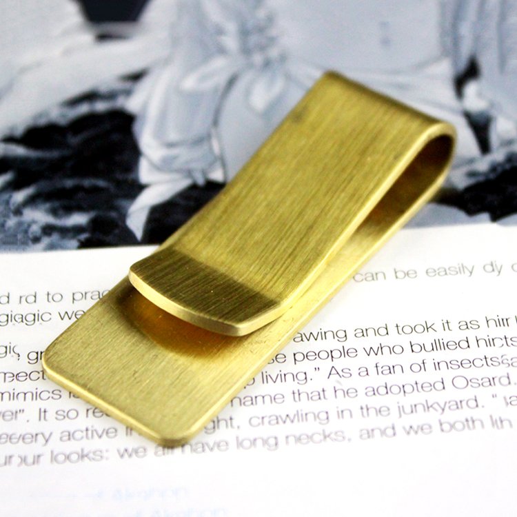 Brass money clip from Fuchsia Molly used as stylish home decor accessory, featuring a sleek, polished finish.