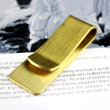 Brass money clip from Fuchsia Molly used as stylish home decor accessory, featuring a sleek, polished finish.