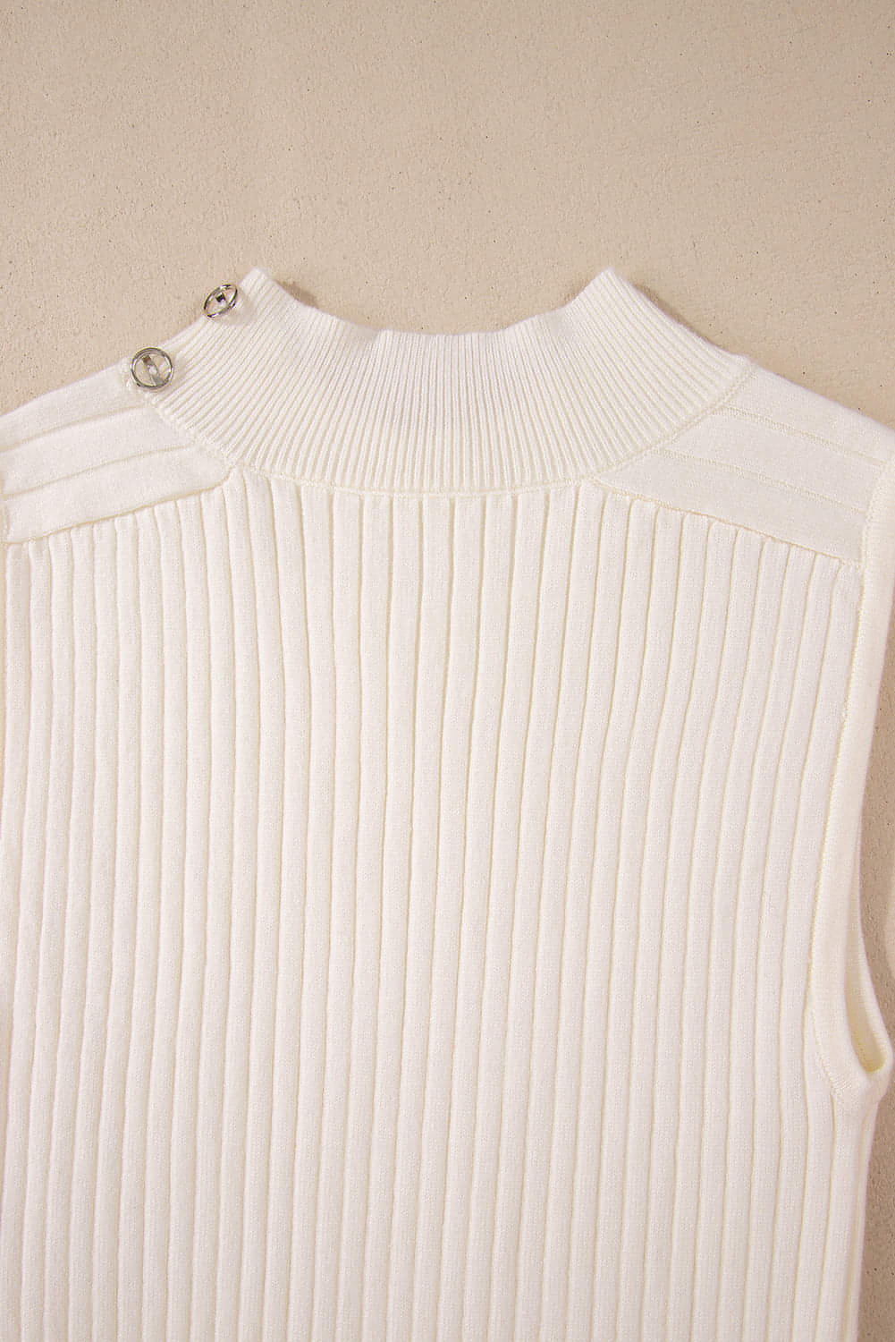 White ribbed knit high neck sweater vest by Carmine Juneberry, close-up of the textured fabric and high neckline.