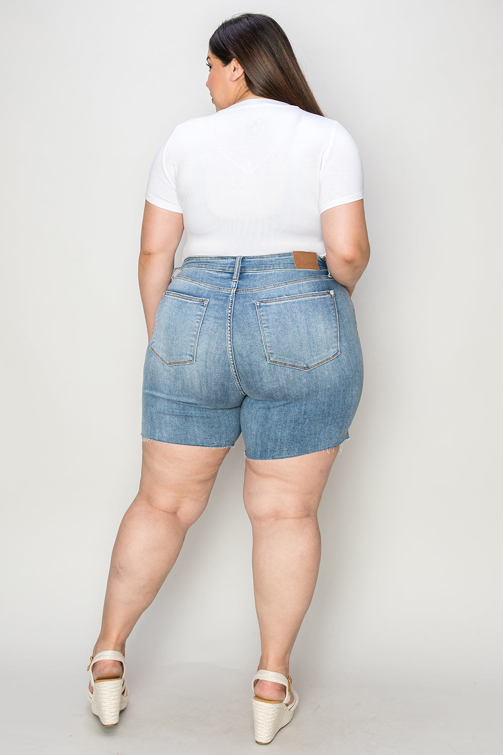 Judy Blue high waist raw hem denim shorts in full size, showcasing classic blue denim with distressed details and frayed edges.