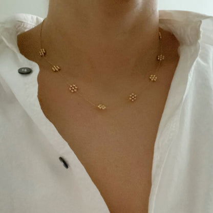 Dainty golden bead flower necklace made of waterproof stainless steel from Fuchsia Hercules, featuring a delicate floral pendant.