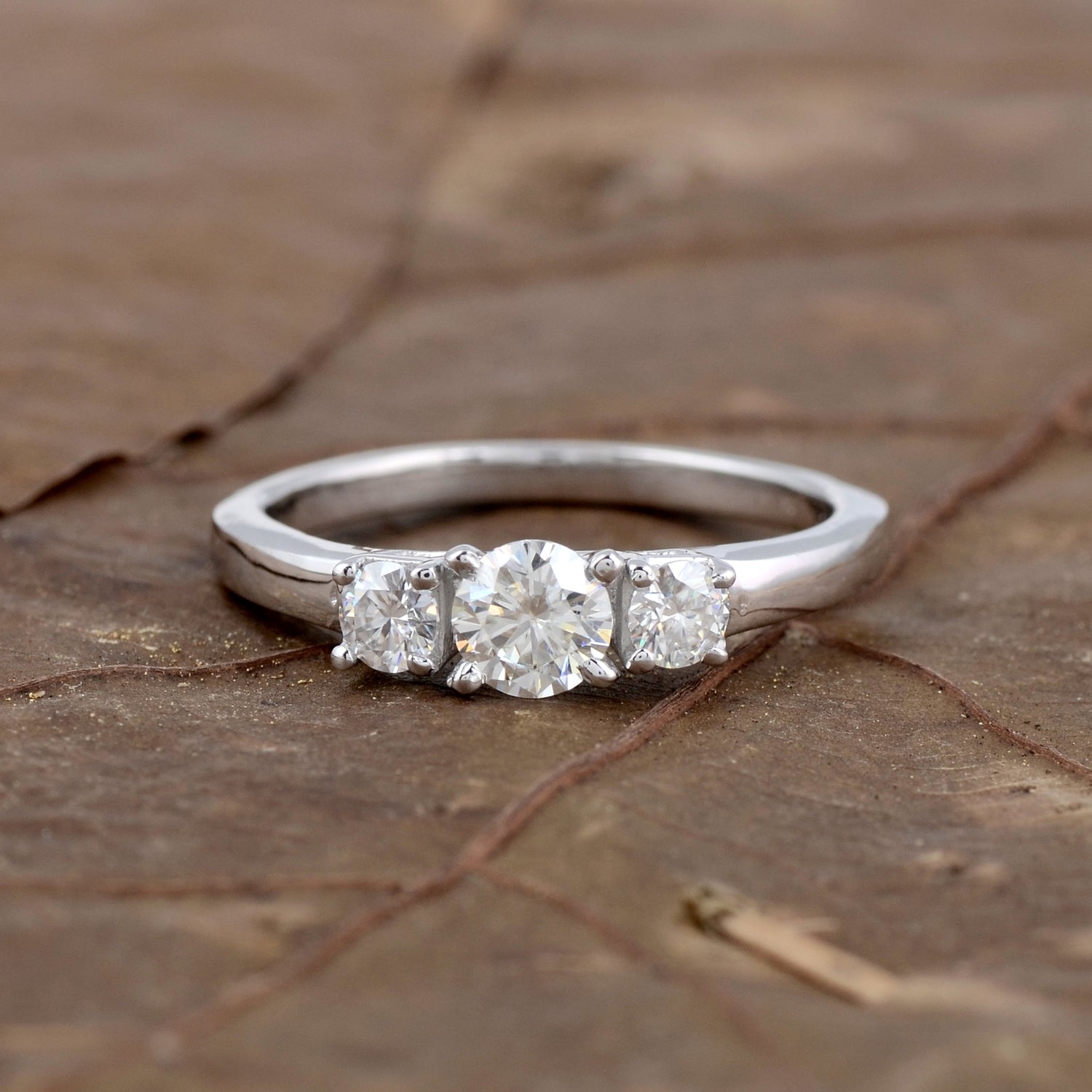 Sterling silver white moissanite 3-stone ring with elegant design, showcasing sparkling gemstones and polished band.