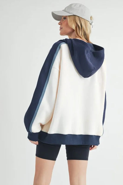 Aemi + Co color block kangaroo pocket hoodie from Pear Daisy, featuring vibrant sections and a cozy hooded design.