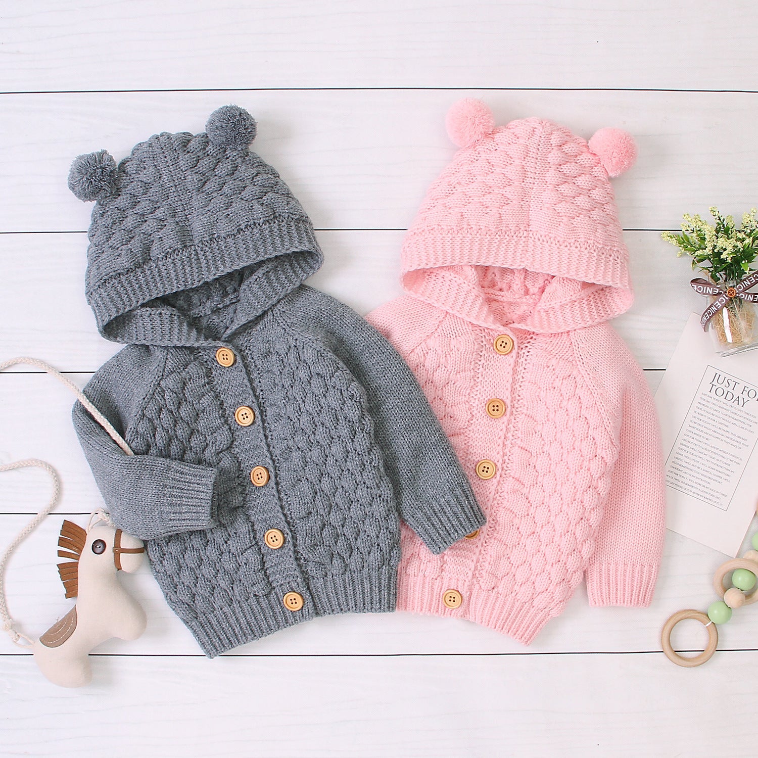 Baby wearing Carmine Juneberry KuschelGlöckchen™ hooded knit jacket with pom-pom, cozy and stylish baby clothing.