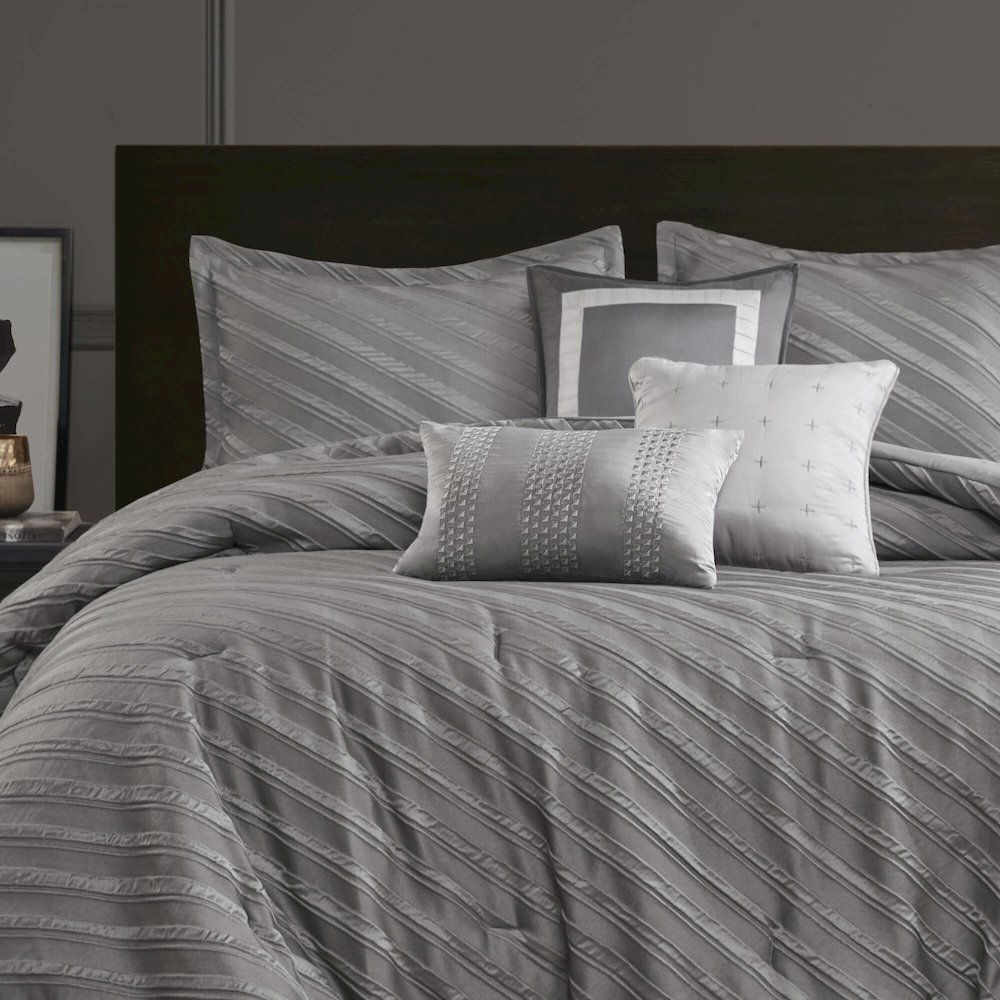 Start2Finish Riva 7-piece grey comforter set with matching pillow shams and decorative pillows on a neatly made bed.