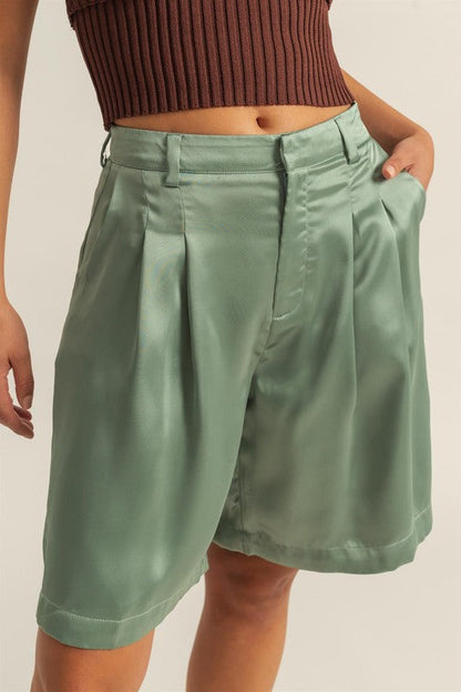 Close-up of Jade Icarus high-waist pleated satin shorts, showcasing shiny fabric, pleats, and high-waist design.
