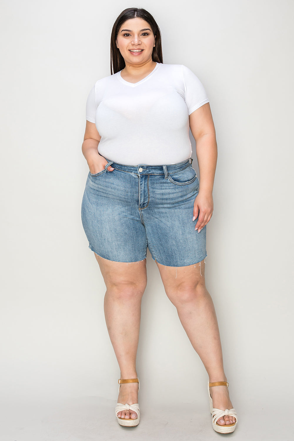 High waist raw hem denim shorts by Judy Blue, styled for a casual look, with distressed detailing on light blue denim fabric.