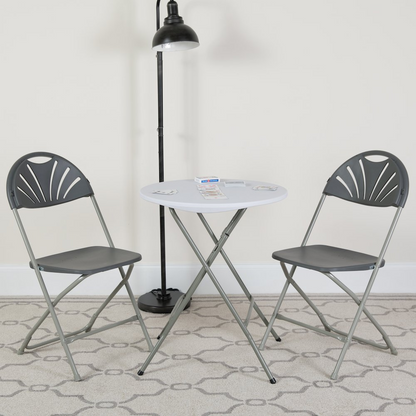Two HERCULES Series 650 lb. capacity charcoal plastic fan back folding chairs by Start2Finish, shown in a folded and upright position.