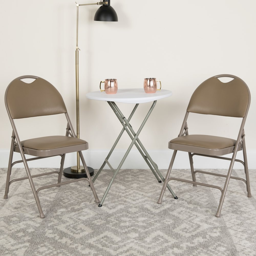 Two beige HERCULES Series vinyl folding chairs by Start2Finish with triple-braced metal frames and easy-carry handles.