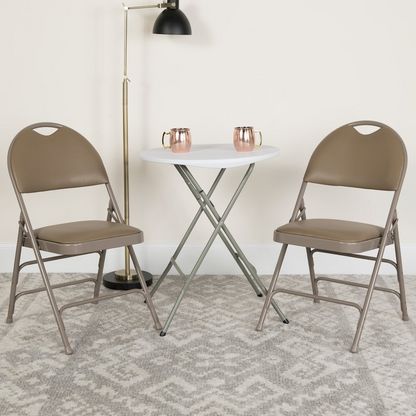 Two beige HERCULES Series vinyl folding chairs by Start2Finish with triple-braced metal frames and easy-carry handles.