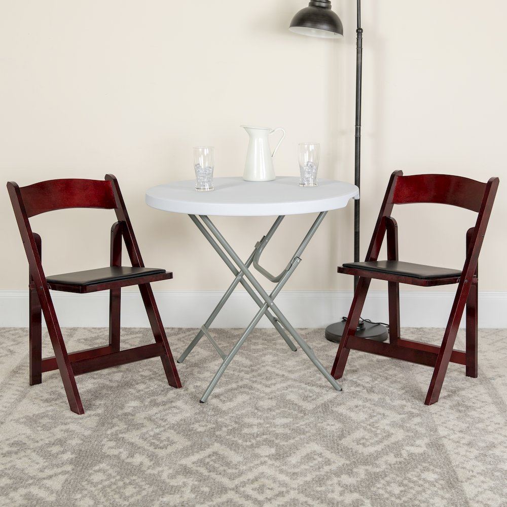 Two HERCULES Series mahogany wood folding chairs from Start2Finish with vinyl padded seats, shown folded and set up for seating.