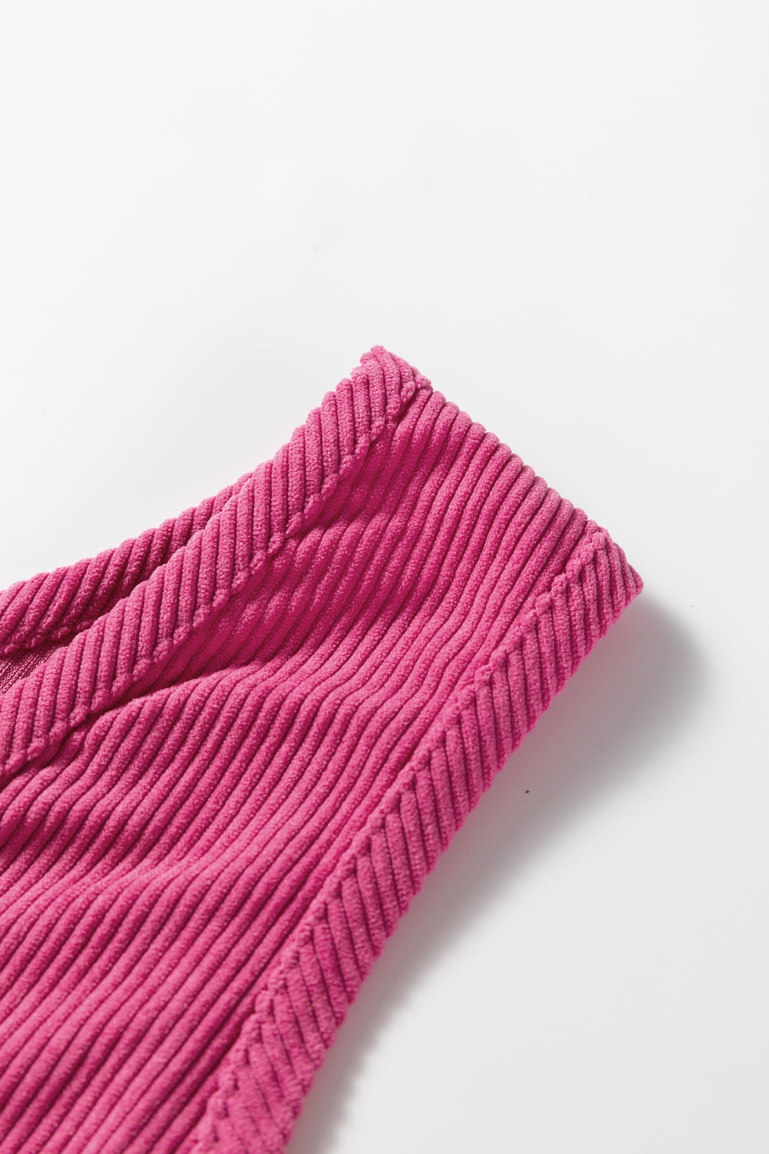 Solid corduroy sleeveless mini dress with front pockets by Byzantium Bay, shown on a hanger.