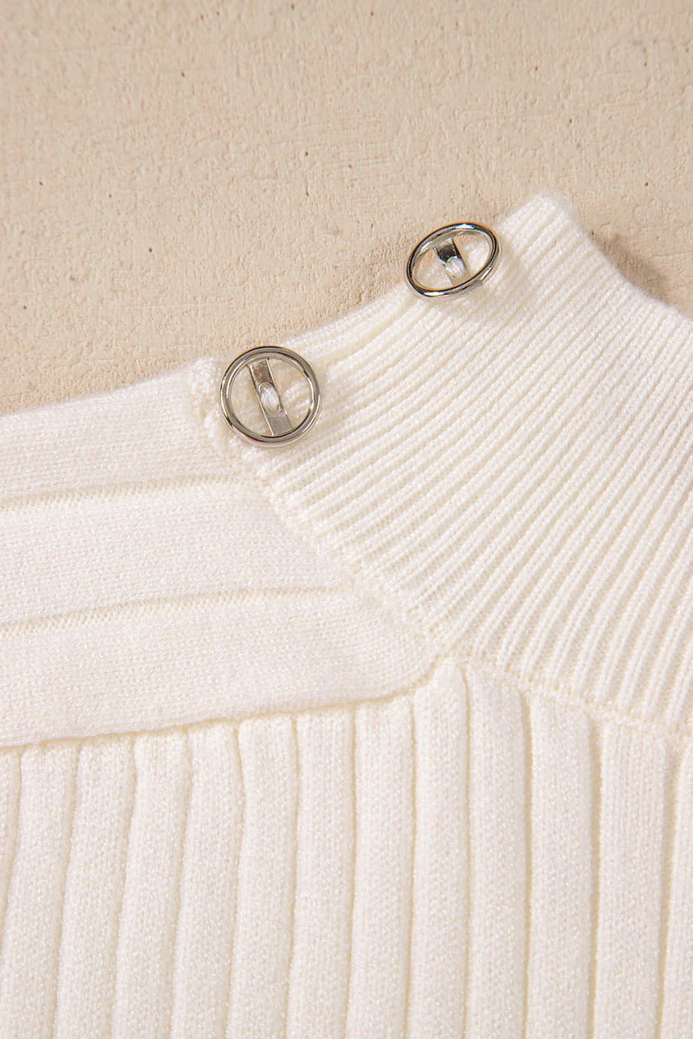 White ribbed knit high neck sweater vest by Carmine Juneberry, showing close-up of textured fabric and high neckline.