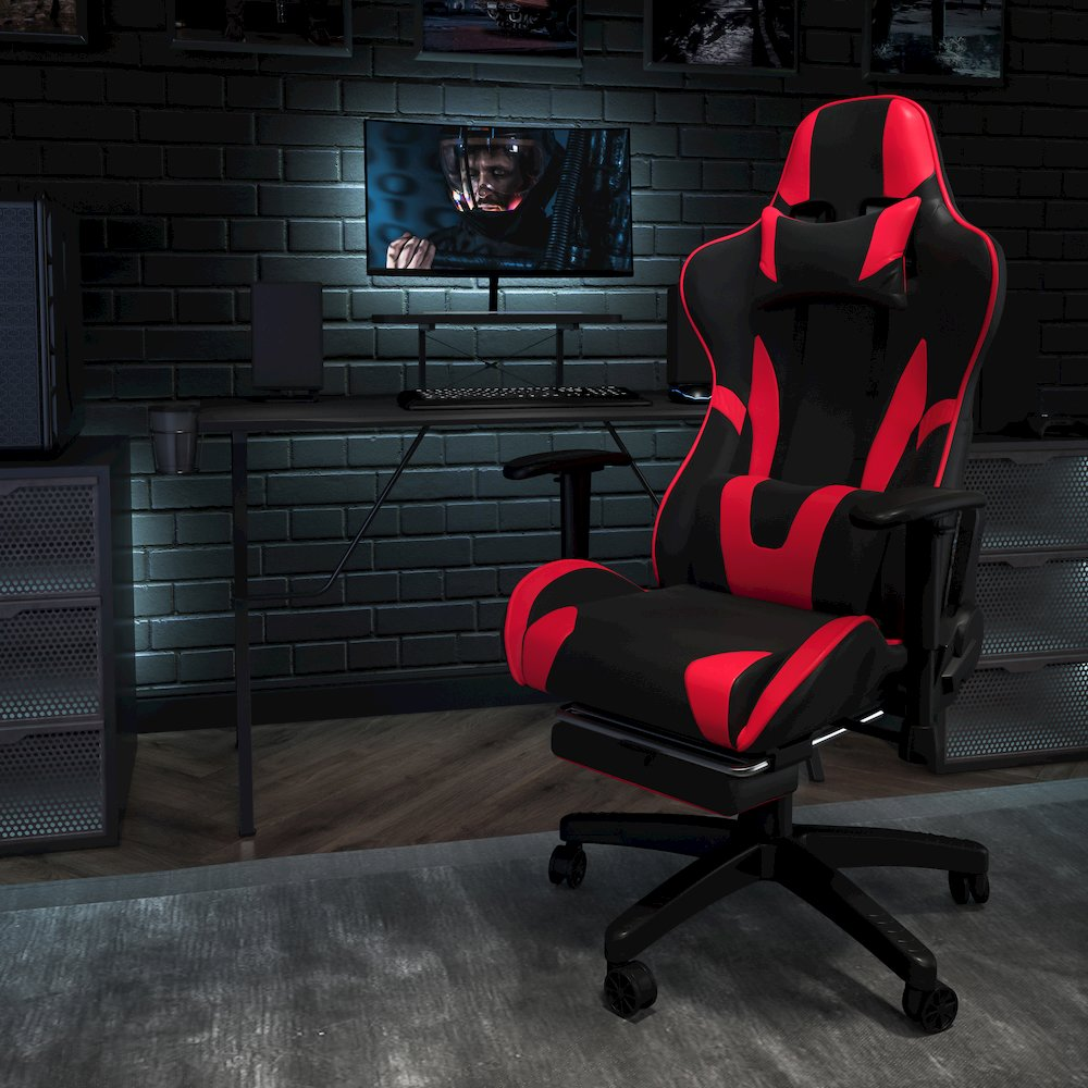 Black gaming desk with a matching red and black gaming chair and footrest, designed for ergonomic gaming setup.