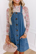 Dusk blue Carmine Juneberry denim mini dress with wide straps, button front, and front pocket detail on a model.