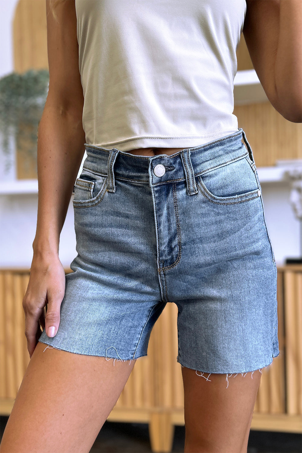 High waist raw hem denim shorts from Judy Blue featuring a stylish fit, shown in a full-size automotive-themed display.