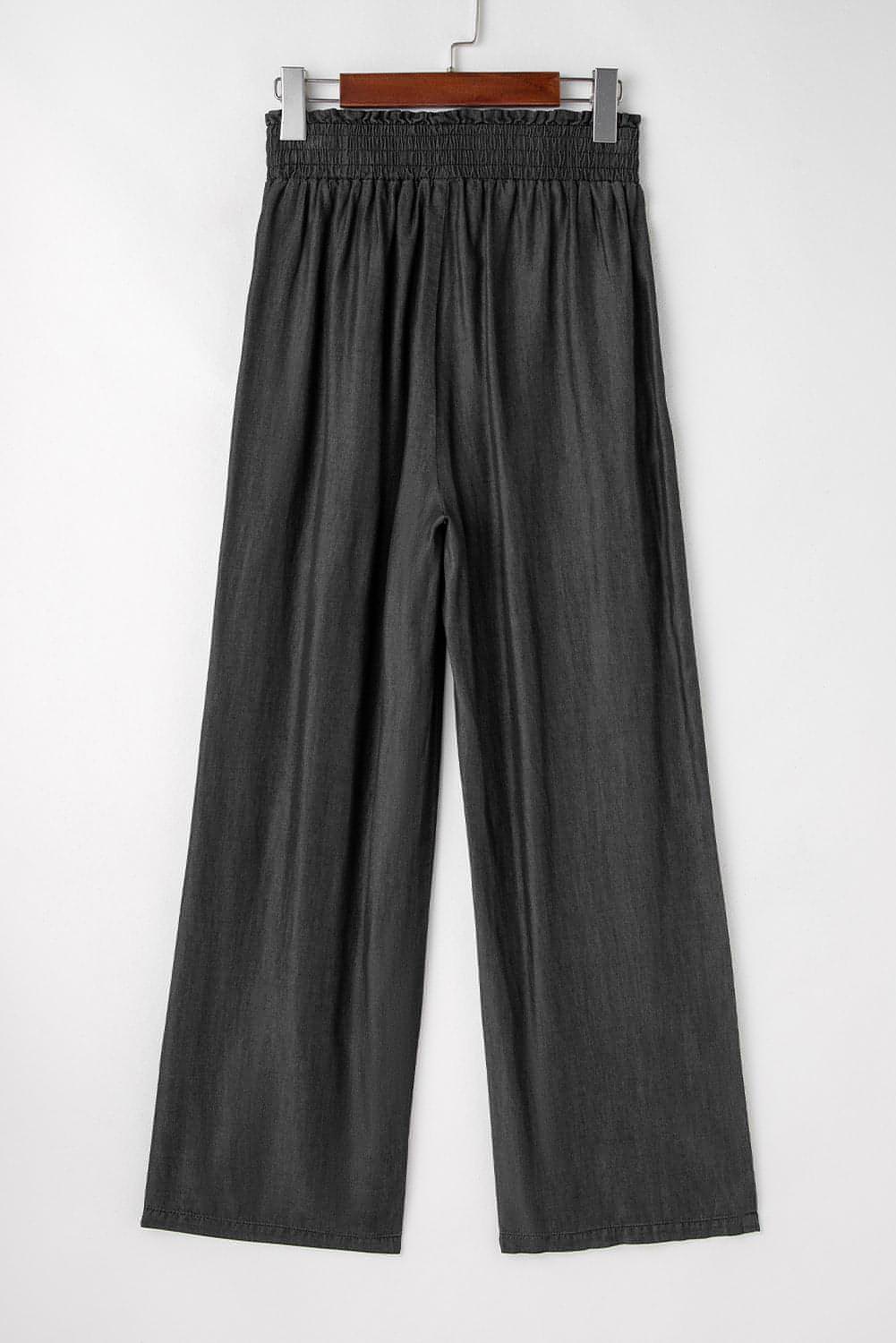 Black high waist wide leg jeans by Carmine Juneberry with side pockets, frilled details, and smocked waistband.