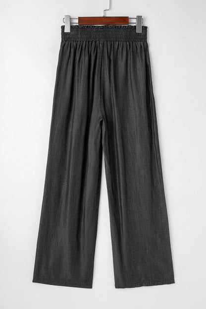 Black high waist wide leg jeans by Carmine Juneberry with side pockets, frilled details, and smocked waistband.