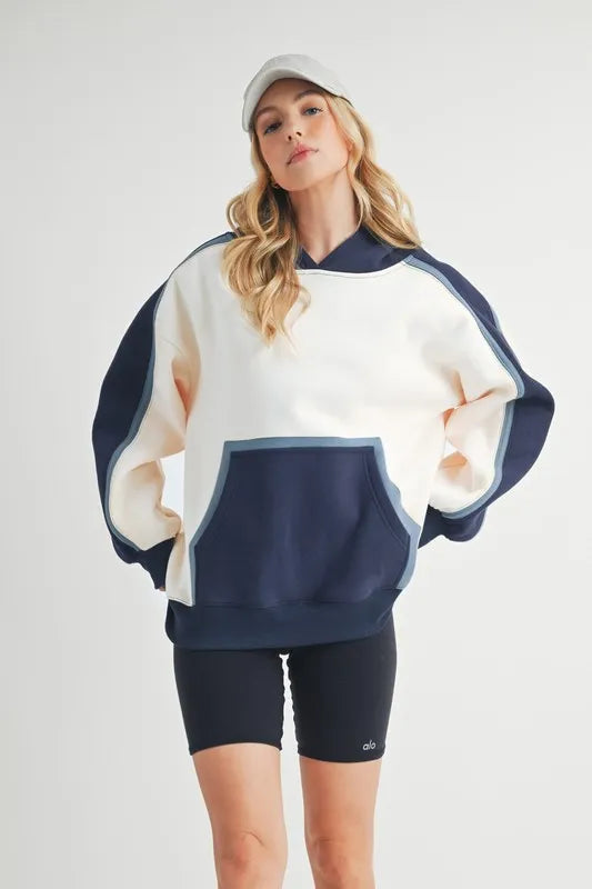 Aemi + Co color block kangaroo pocket hoodie by Pear Daisy, featuring a cozy, stylish design with bold color blocks and a front kangaroo pocket.