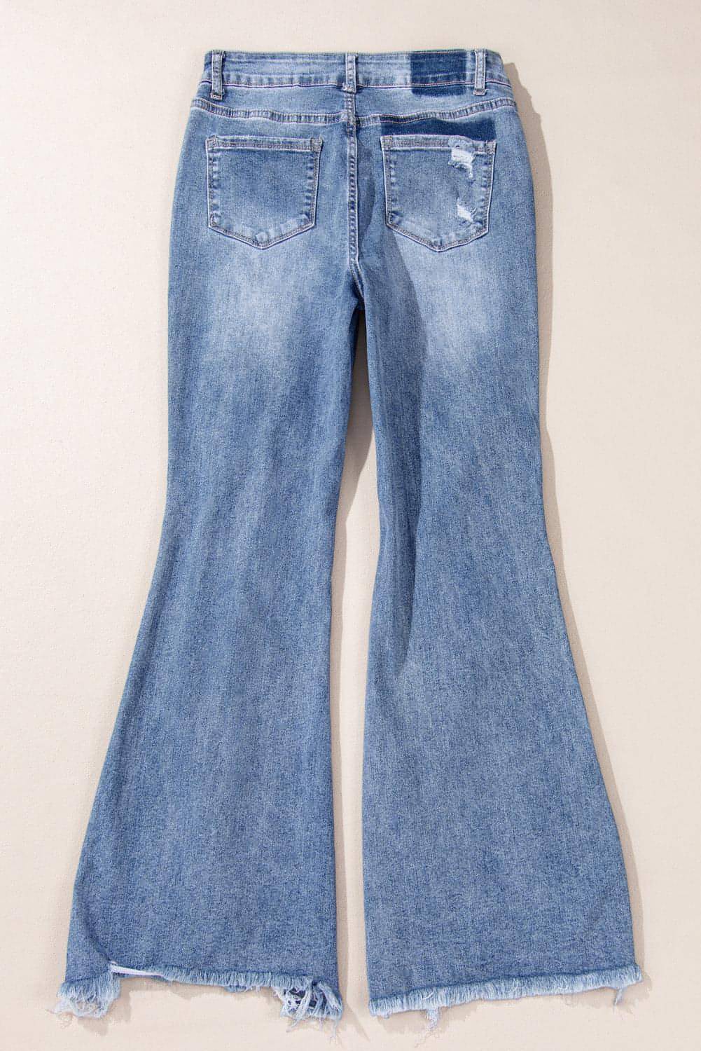 Dusk blue high rise ripped distressed hem flared jeans by Carmine Juneberry displayed on a model.