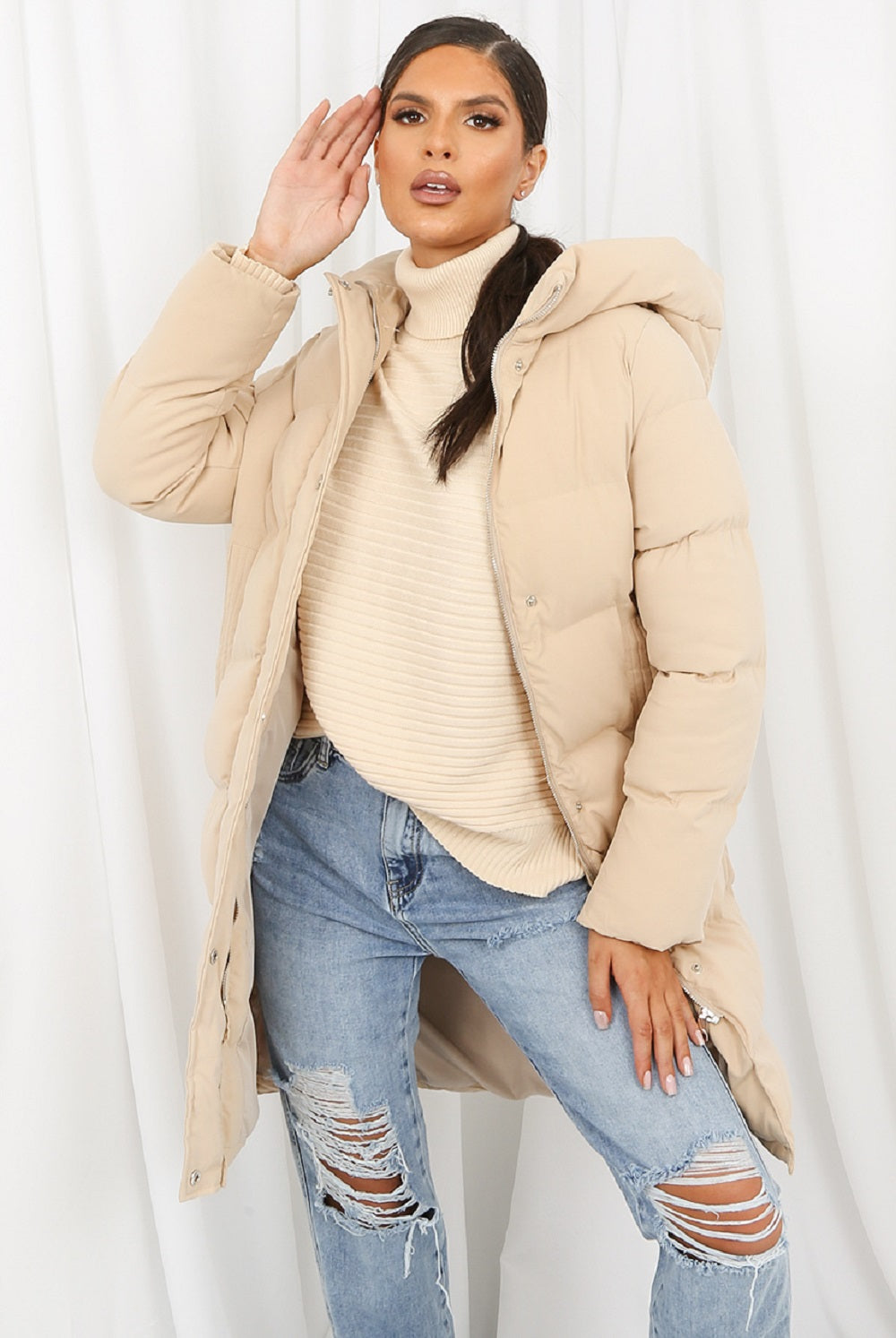Beige hooded longline puffer coat by Rose Eleusis, featuring a quilted design, oversized fit, and warm padded insulation.