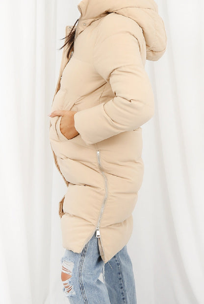 Beige hooded longline puffer coat by Rose Eleusis, showcasing its quilted design and cozy, insulated winter style.