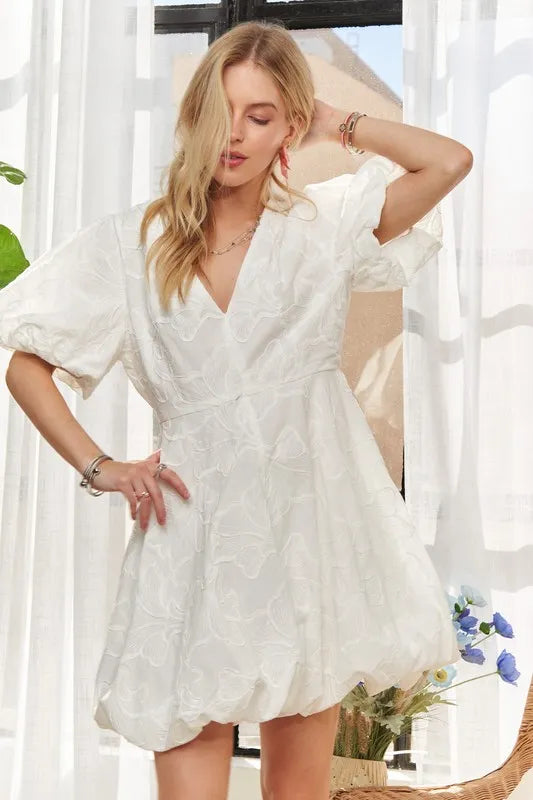 Pear Daisy ADORA puff sleeve floral dress displayed on a hanger with a garden background, showcasing the dress&