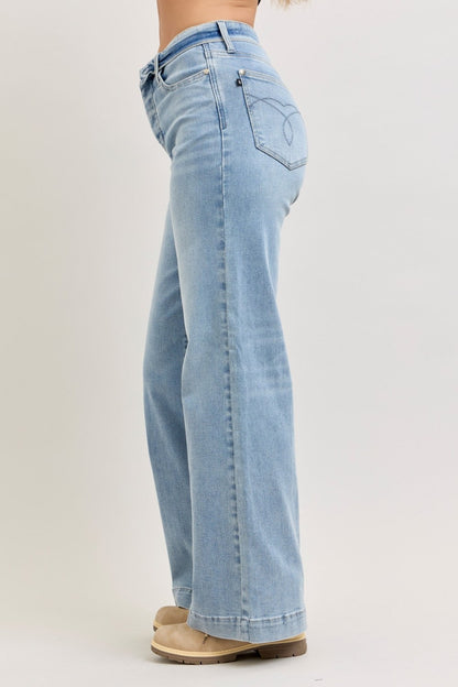Pear Daisy Judy Blue mid-rise retro wide leg jeans with fold-over waistband, displayed on a hanger in a home setting.