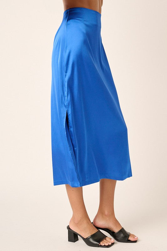 Jade Icarus Mittoshop satin midi skirt with side slit, showcasing smooth fabric and elegant design in a stylish automotive-inspired setting.