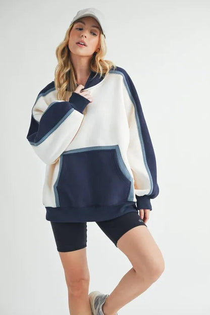 Aemi + Co color block kangaroo pocket hoodie by Pear Daisy, featuring a cozy, stylish design with a front pocket and vibrant color blocks.