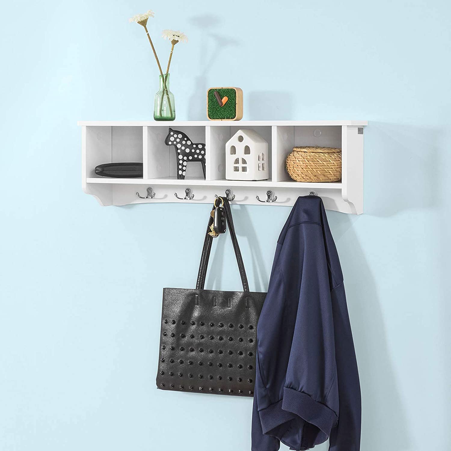 White wall shelf coat rack by Carmine Deianeira with hooks, mounted on a wall in a home or garden setting.