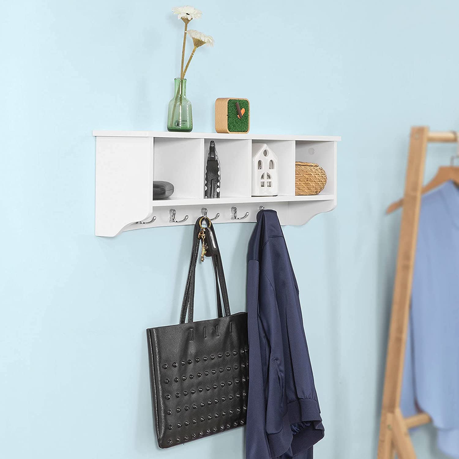 White wall shelf coat rack by Carmine Deianeira, mounted on a wall with hooks for hanging items in a home or garden setting.