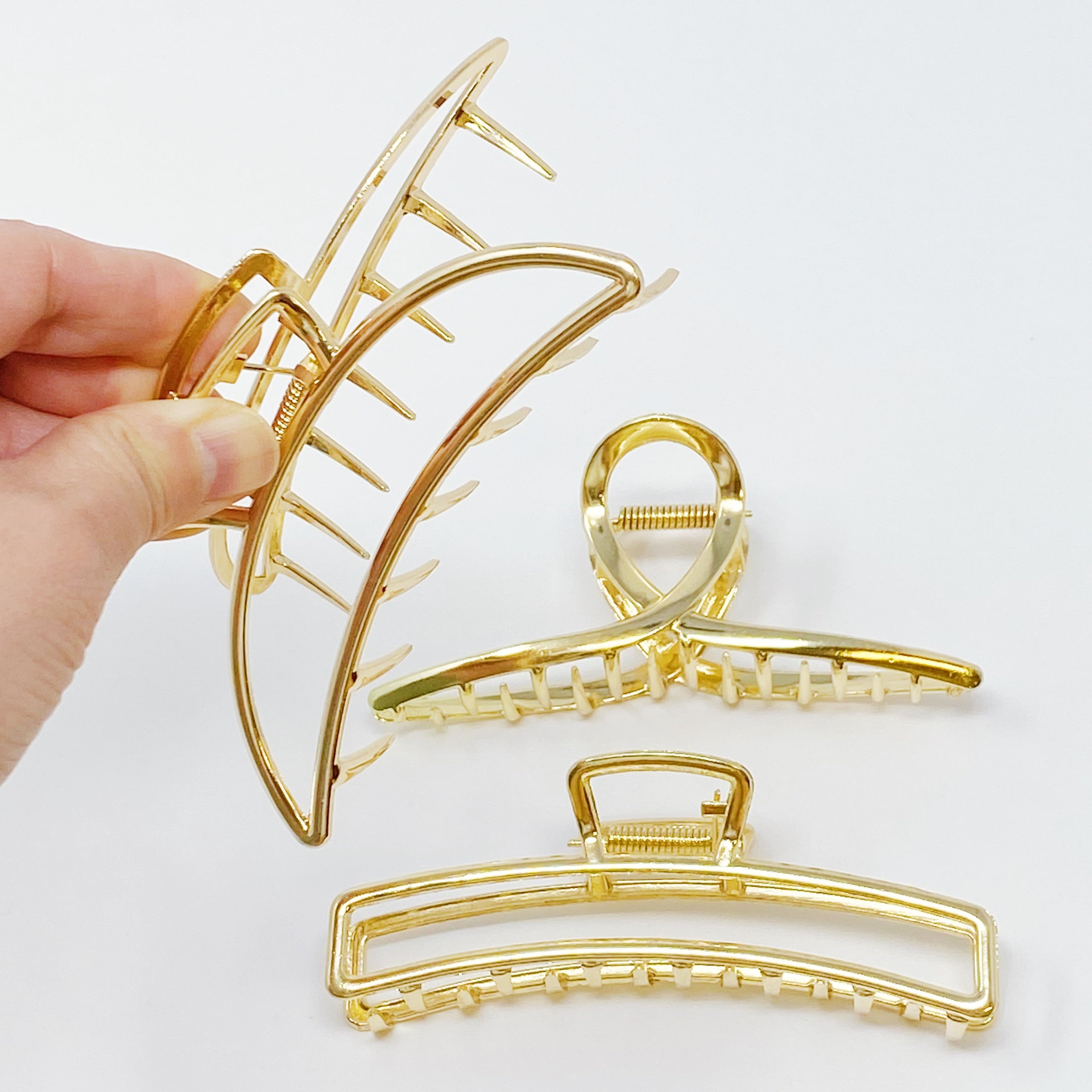 Set of three gold hair claw clips from Fuchsia Hercules, stylish jewelry accessories for holding hair securely.