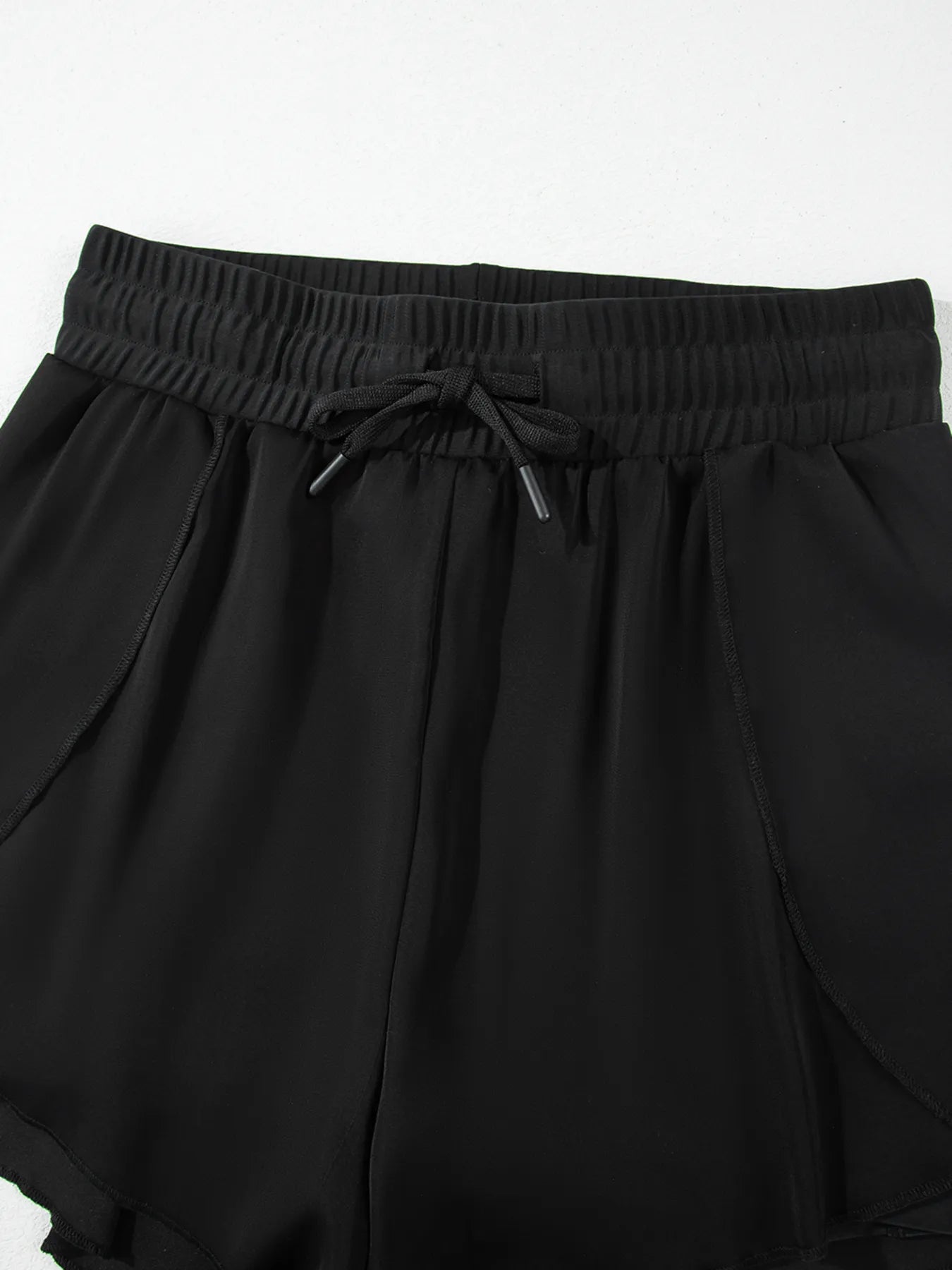 Pear Daisy high waisted drawstring swim shorts with a relaxed fit, displayed on a hanger with a light background.