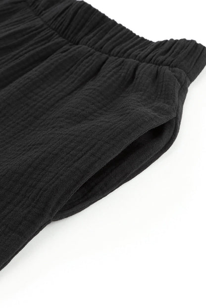 Black textured high waist ruffled bell bottom pants by Carmine Juneberry, showcasing flowy fabric and stylish bell-shaped cuffs.